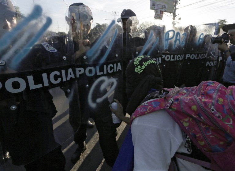 Un joven protestante pinta el escudo de los policías en Managua, Nicaragua.