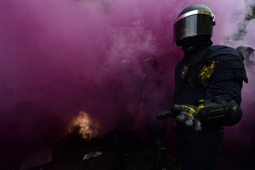 La policía de Barcelona tira una bomba de gas en los disturbios desatados tras la detención del ex presidente de Cataluña, Carles Puigdemont, en Alemania.