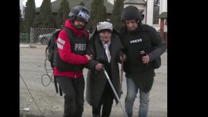 El corresponsal de la TRT ayuda a una anciana ucraniana durante la evacuación